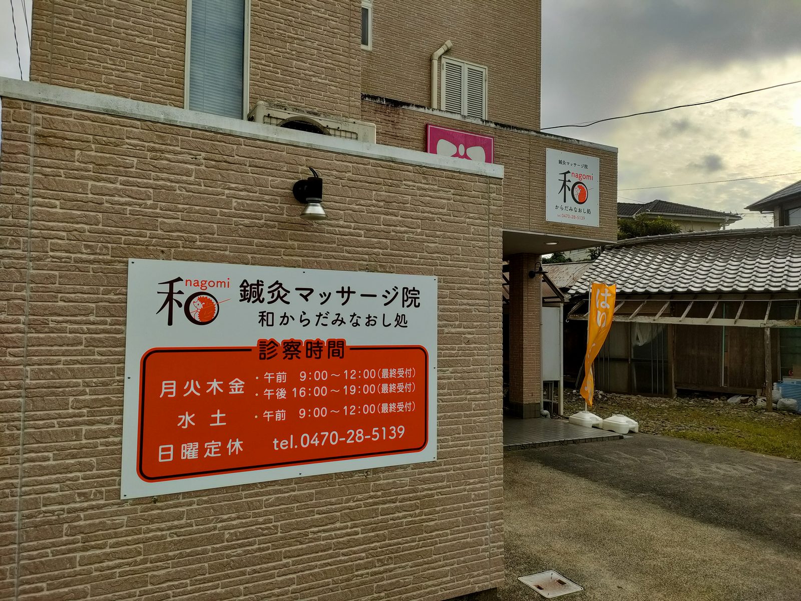 院名と施術時間・電話番号が書かれた、建物の壁の新しい看板